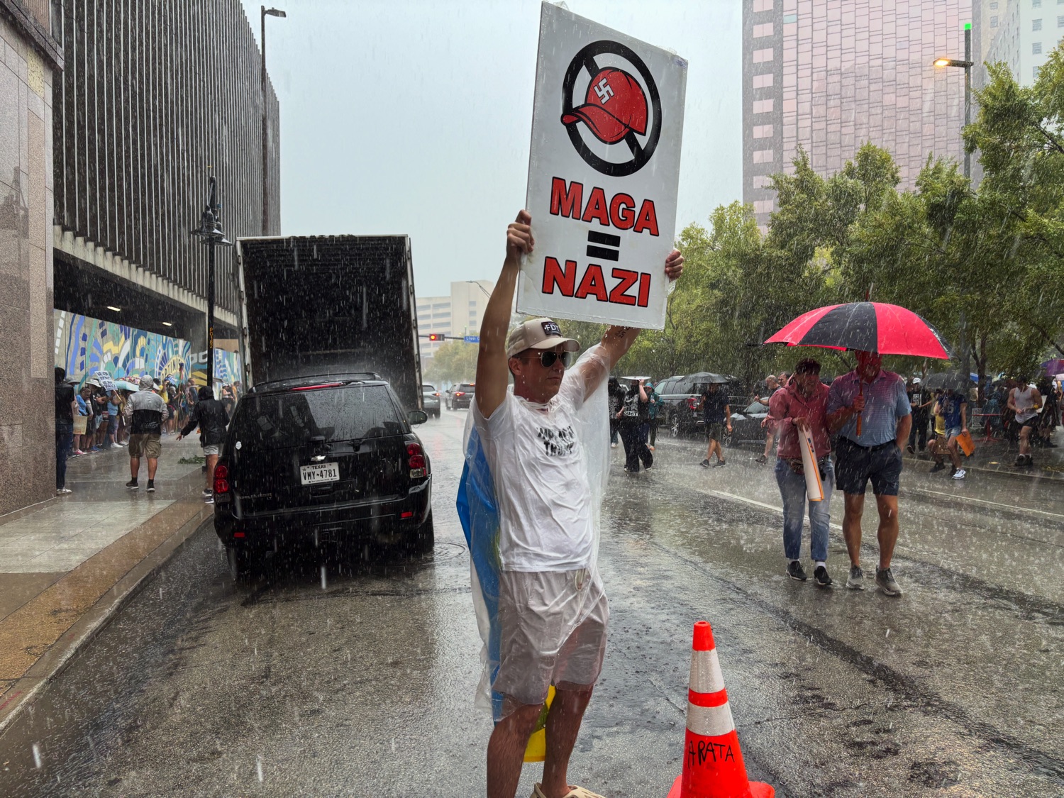 A Dallas protester at October's No Kings rally holds an anti-MAGA sign in the rain.